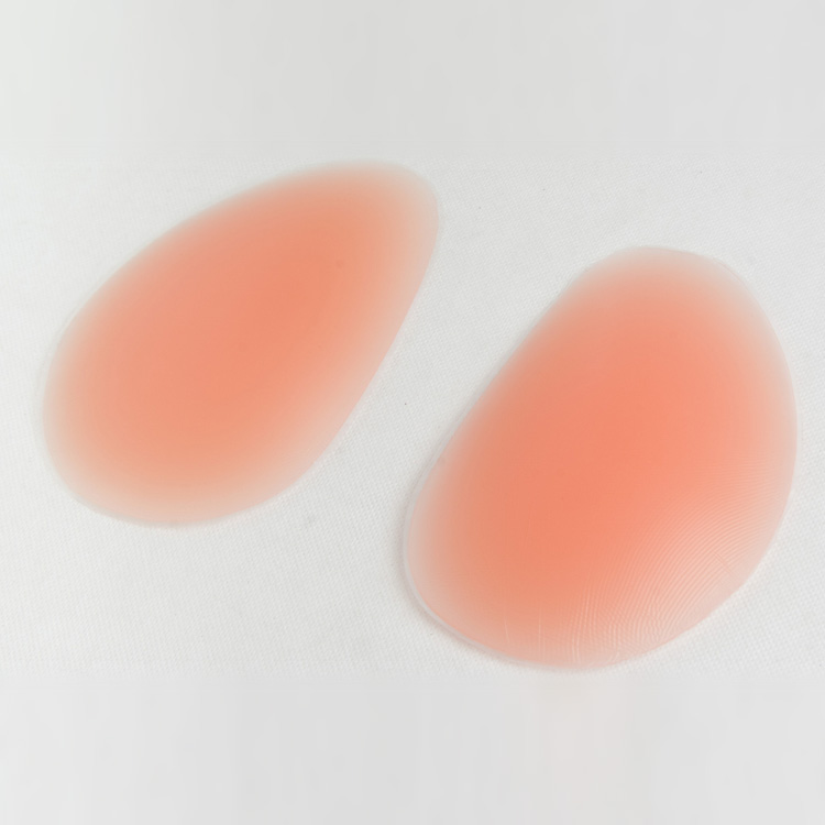 Two matte silicone butt lift pads in one nude tone with feathered edges on a white background