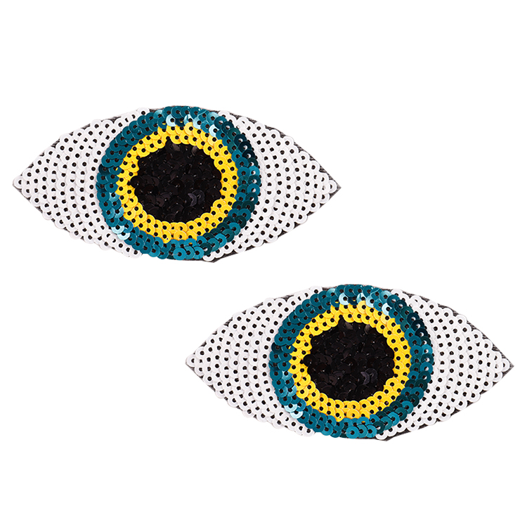 Pair of sequined eye shaped pasties with black, yellow and blue discs on a white background