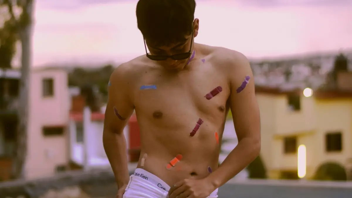 Shirtless male runner with coloured tape strips on his chest and arm after a run