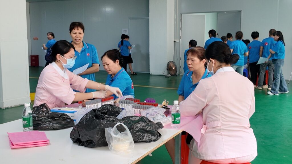 Nurse in pink uniform collecting a blood sample from an employee during Xinke 2026 annual employee health check-up at the company site